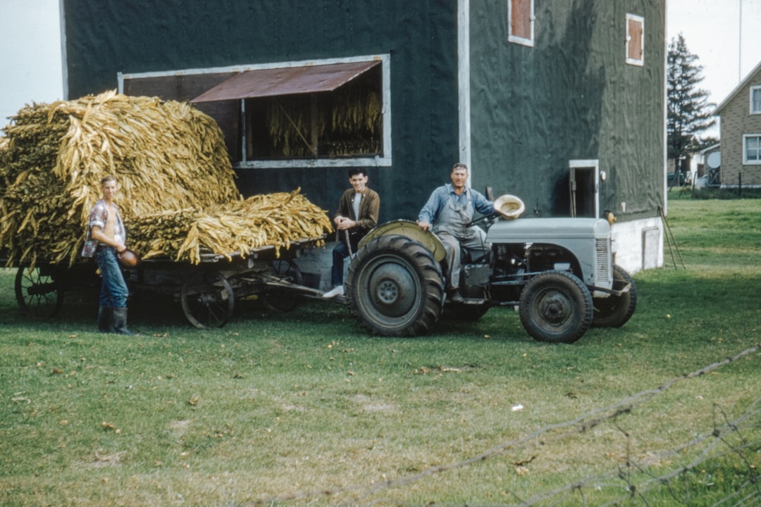 man in white long sleeve shirt riding on tractor during daytime