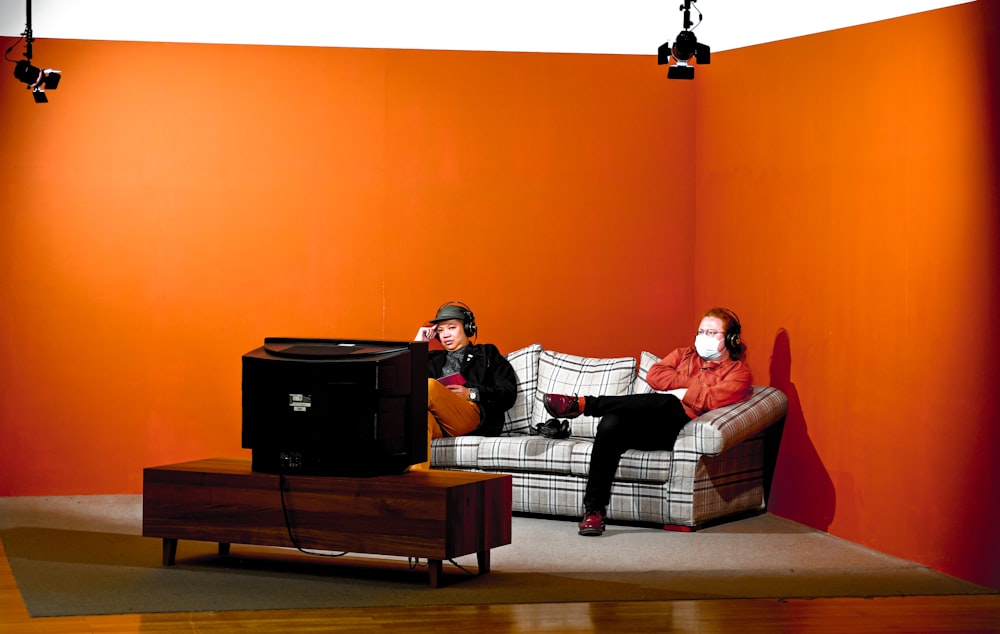 man and woman sitting on brown and white plaid sofa chair