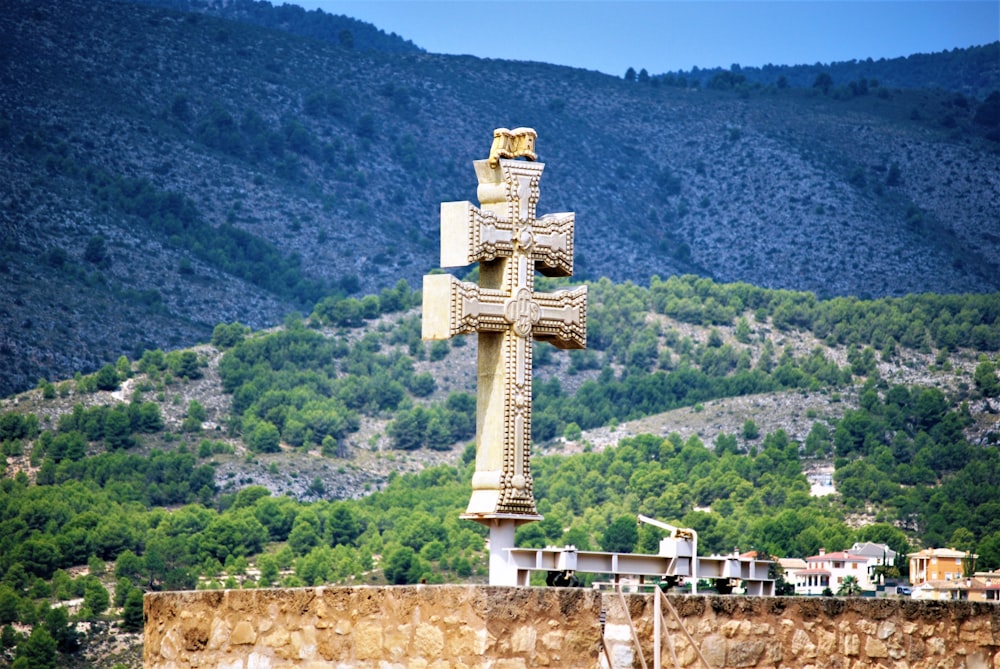white and brown concrete cross on top of mountain during daytime