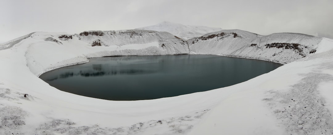 lake in the middle of snow covered mountains