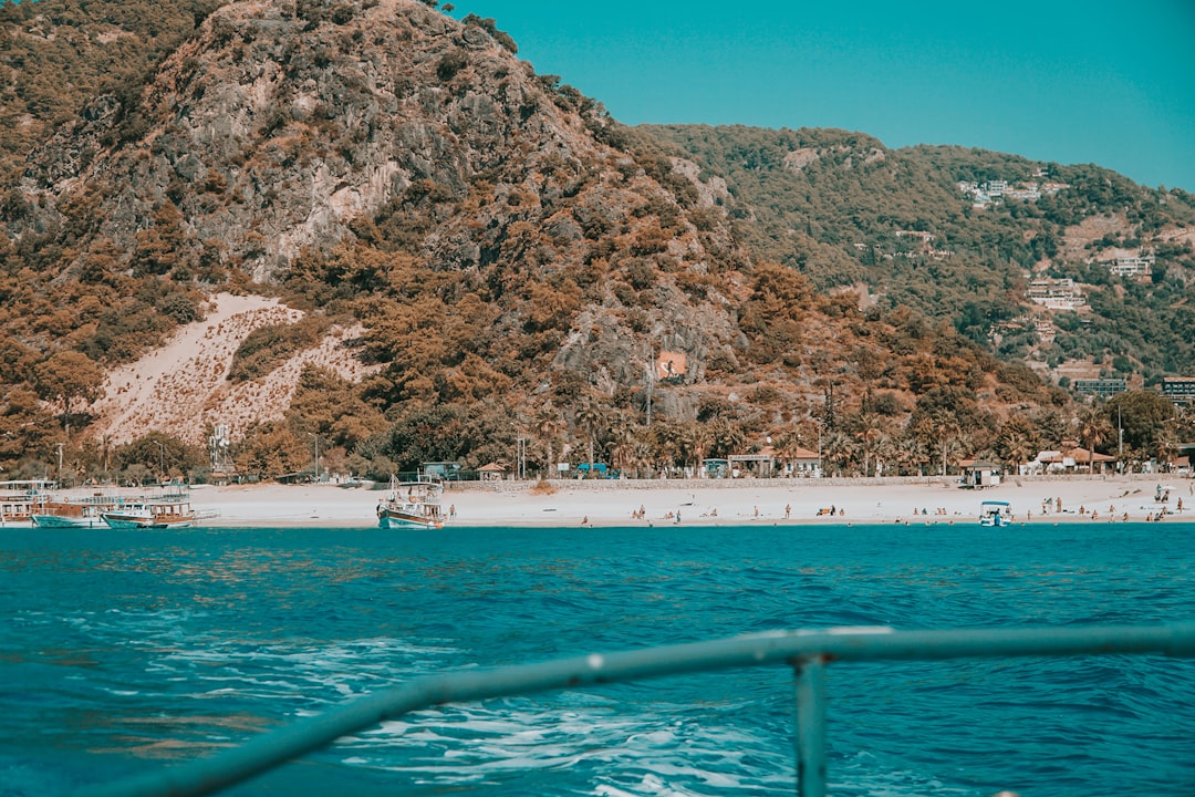 white boat on sea near brown mountain during daytime