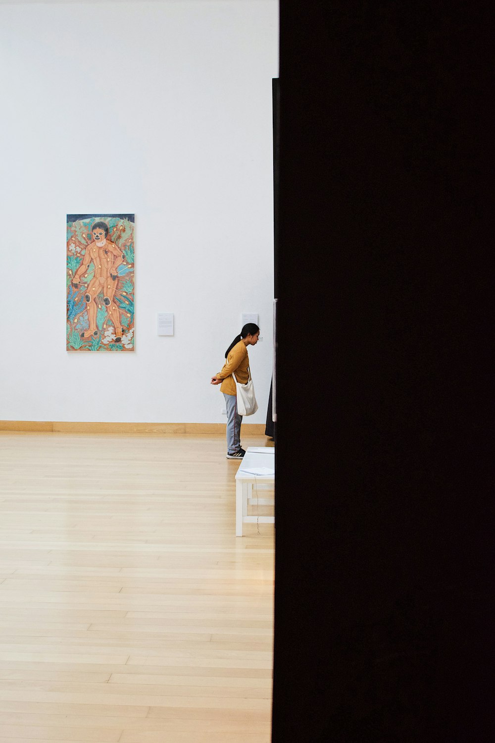 man in white t-shirt and blue denim jeans standing on brown wooden floor