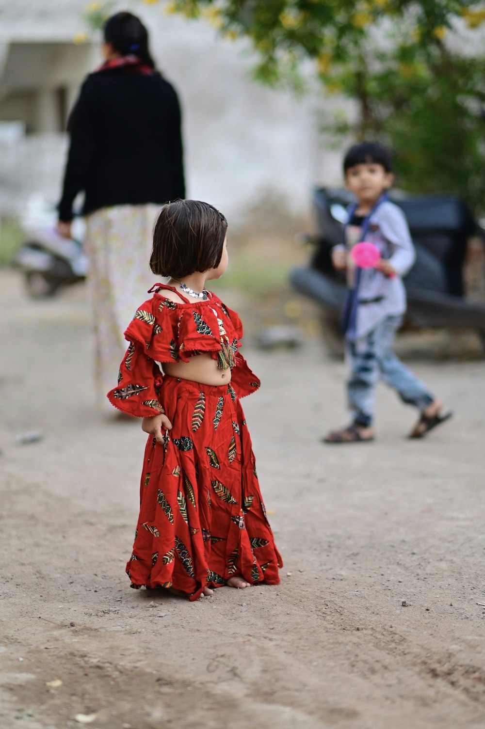 girl in red and white floral dress walking on gray sand during daytime