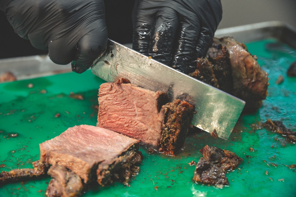 person holding sliced meat on green chopping board