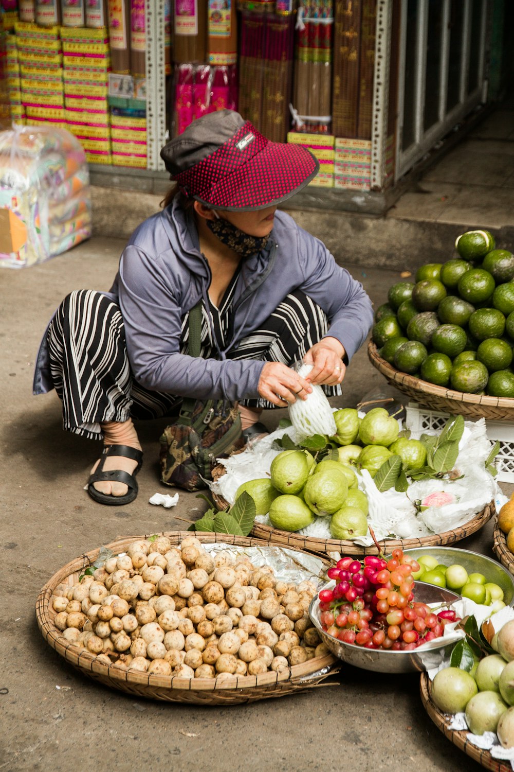Femme en chemise à manches longues à rayures noires et blanches tenant des fruits ronds verts