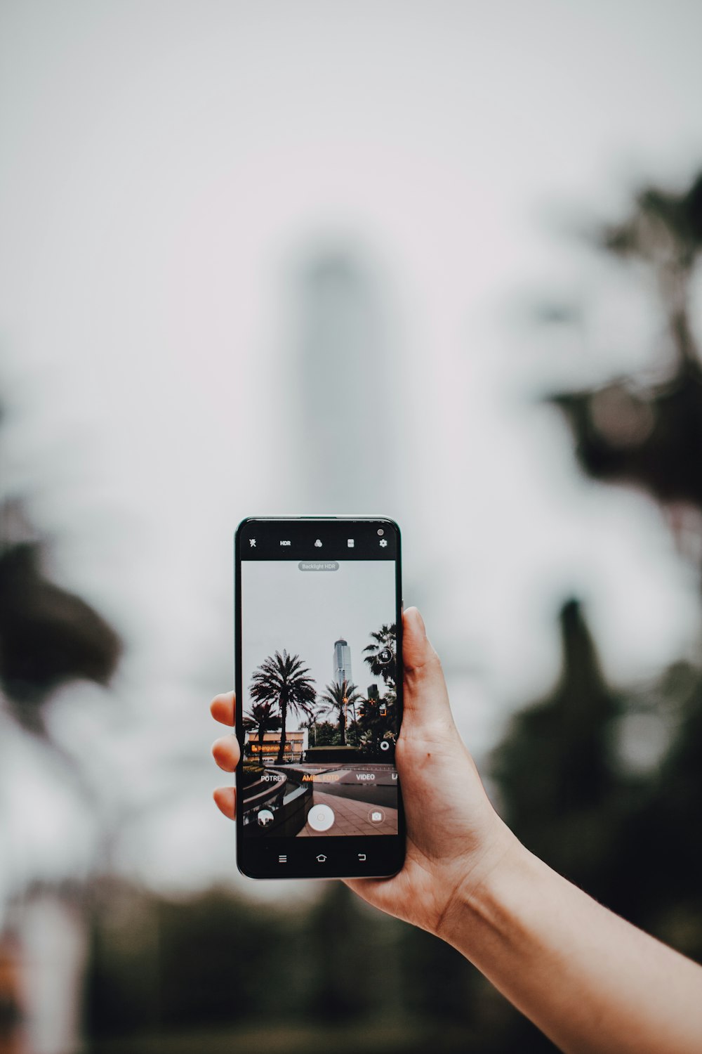 person holding black smartphone taking photo of water fountain