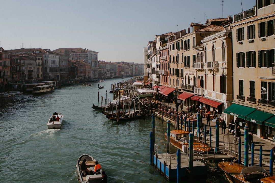 people riding on boat on river between buildings during daytime