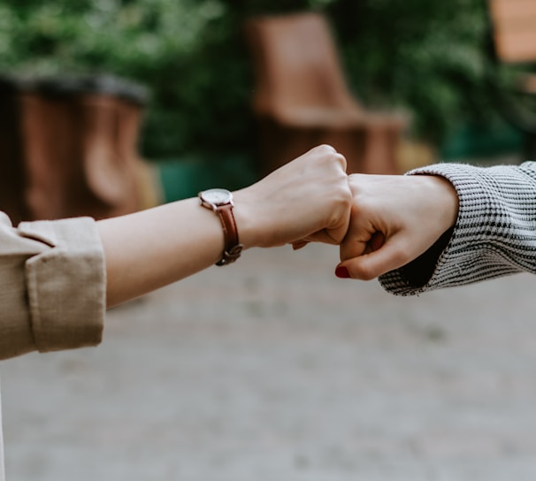 person in black and white long sleeve shirt holding hands with woman in brown coat during