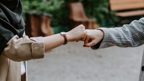 person in black and white long sleeve shirt holding hands with woman in brown coat during