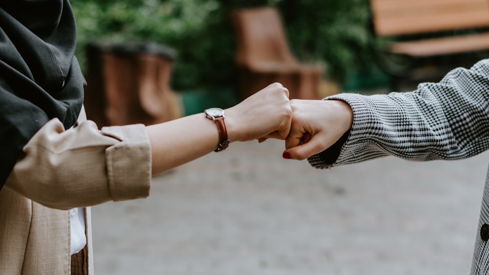 person in black and white long sleeve shirt holding hands with woman in brown coat during