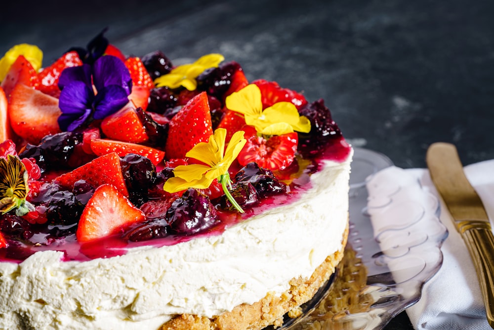 white cake with sliced strawberries and blueberries on top