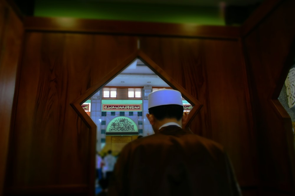 man in black coat standing near brown wooden door