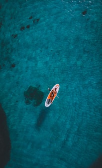person riding on white and red surfboard on body of water during daytime