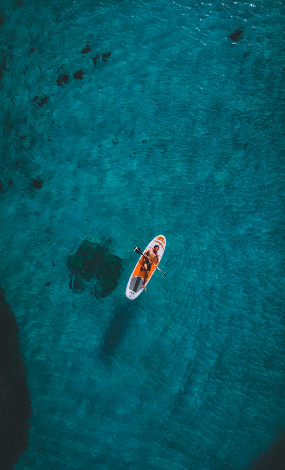 person riding on white and red surfboard on body of water during daytime