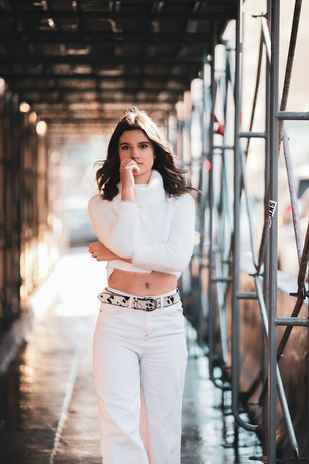 woman in white long sleeve shirt and blue denim jeans standing on bridge during daytime