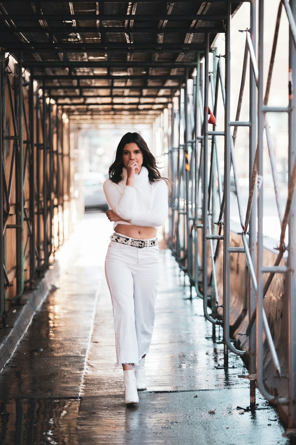 woman in white long sleeve shirt and white pants standing on brown wooden bridge during daytime