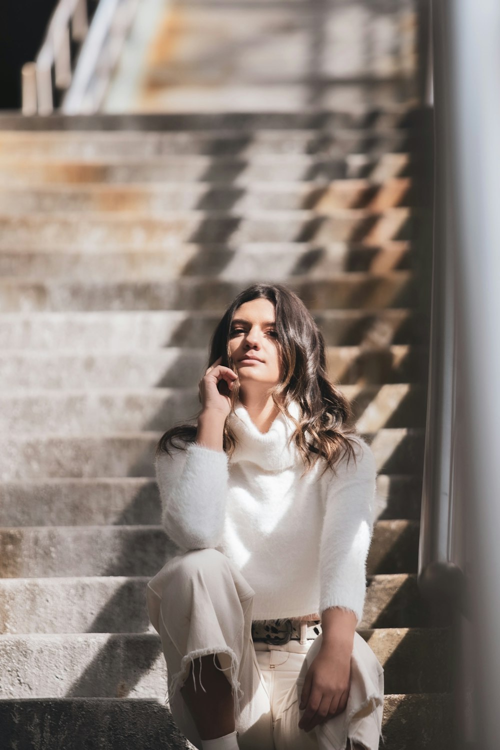 woman in white sweater and black sunglasses sitting on stairs