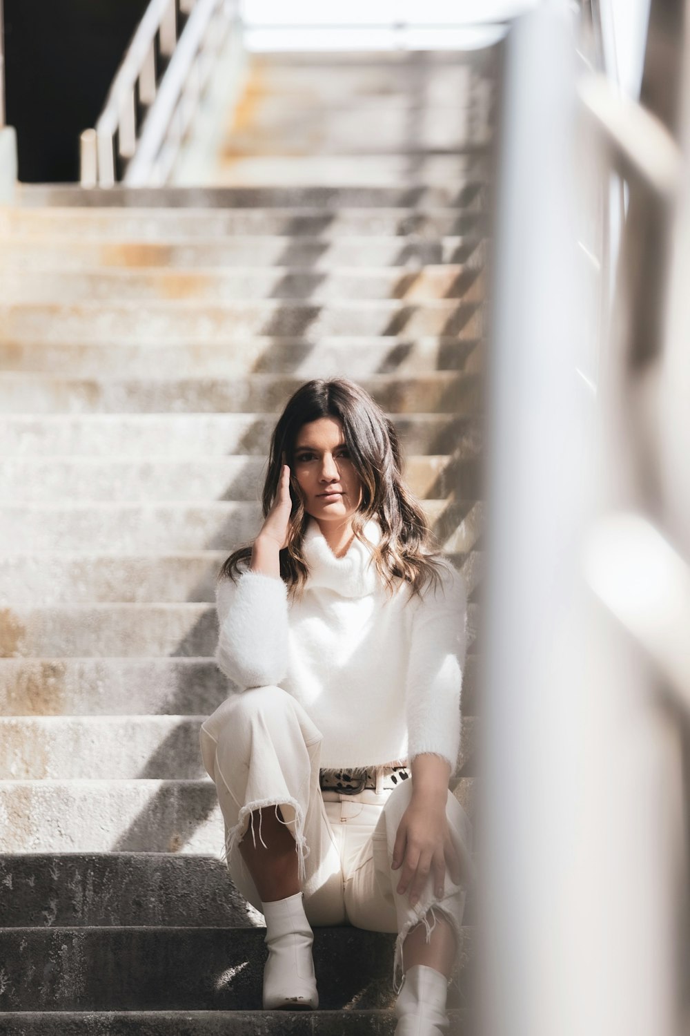 woman in white long sleeve shirt and black pants sitting on brown concrete stairs