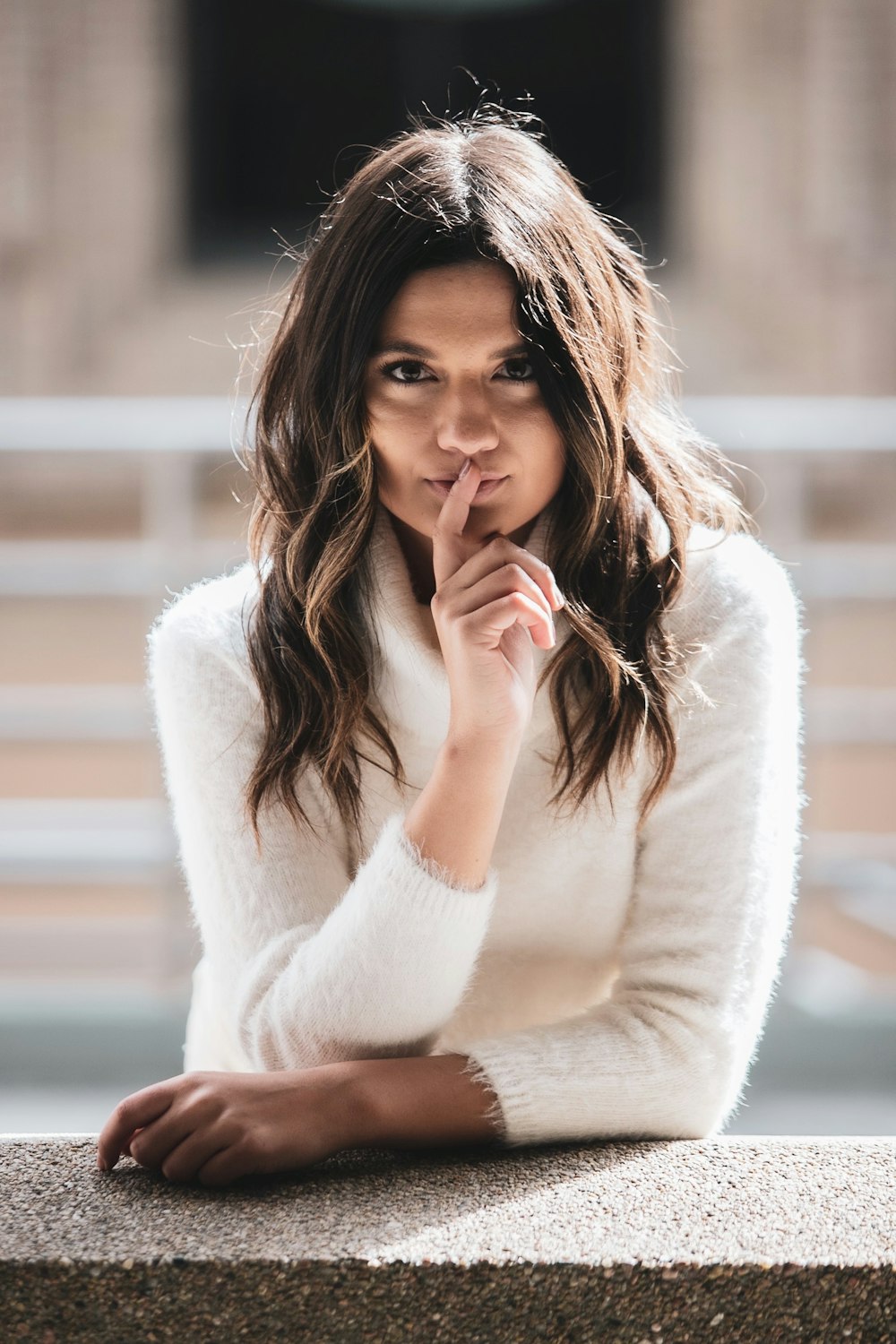 woman in white sweater holding her chin