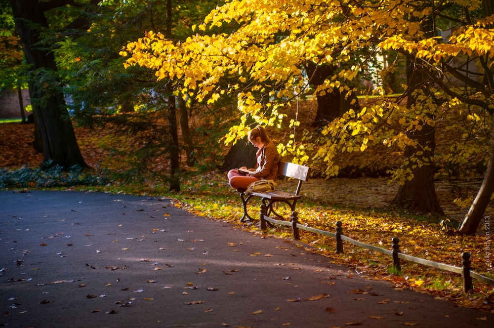 woman in white shirt sitting on bench during daytime