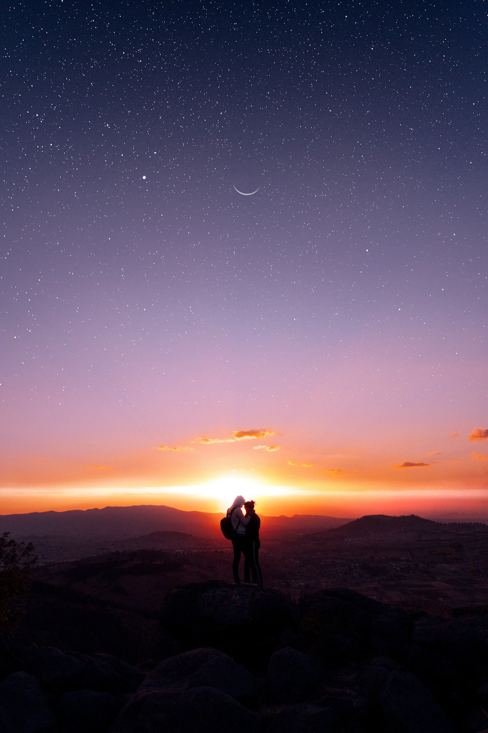 silueta del hombre y de la mujer de pie en la cima de la montaña durante la noche