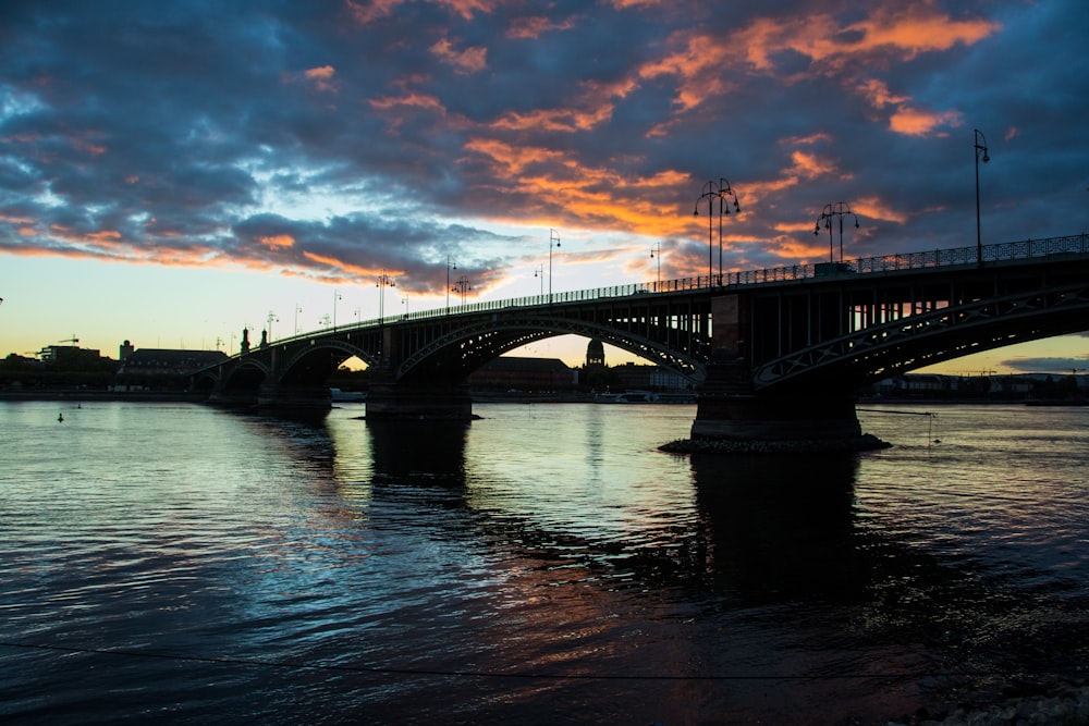 Pont en béton gris au-dessus d’un plan d’eau au coucher du soleil