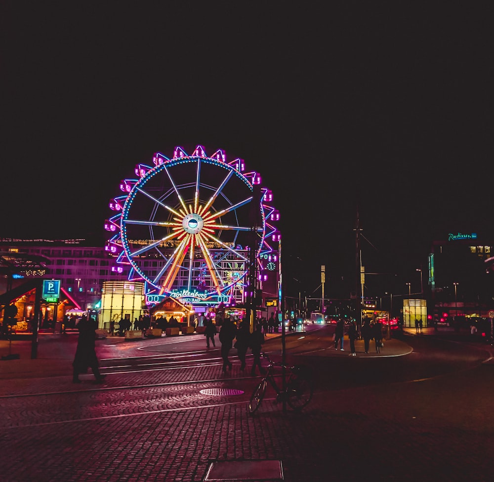 a ferris wheel lit up at night in a city