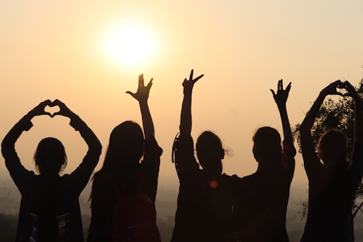 A vibrant sunrise over the savannah in Roraima, with silhouettes of people holding hands forming a sun shape.
