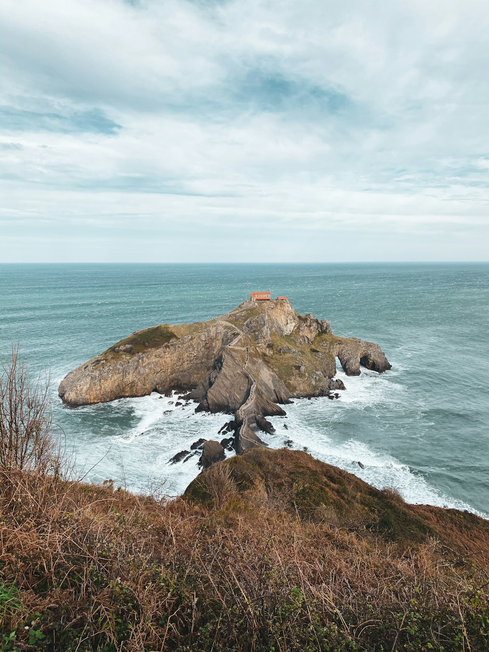 brown rock formation on sea under white clouds during daytime