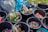 Several buckets are filled with various discarded items such as empty glass bottles, plastic bottle caps, and metal lids. Surrounding the buckets are large garbage bags in shades of grey and blue. Some buckets contain mixed debris including cans and wrappers.