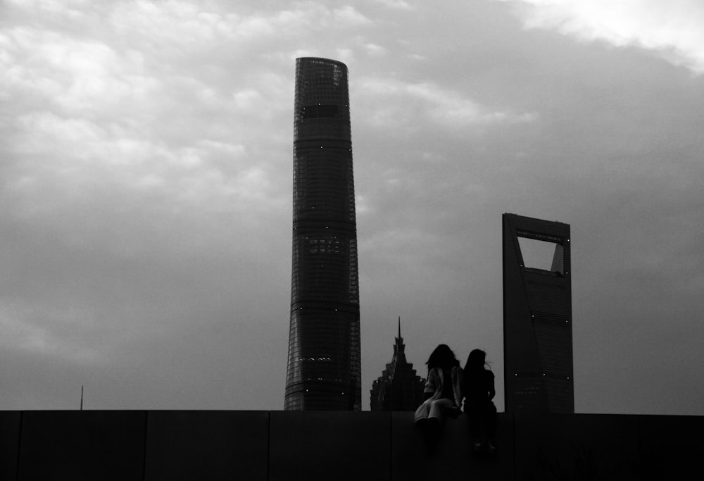 grayscale photo of people walking on street near high rise building