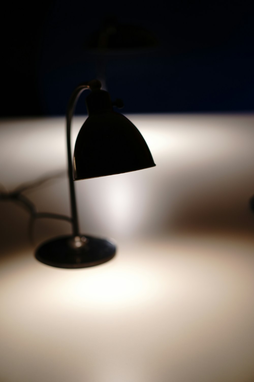 black desk lamp turned on in dim light