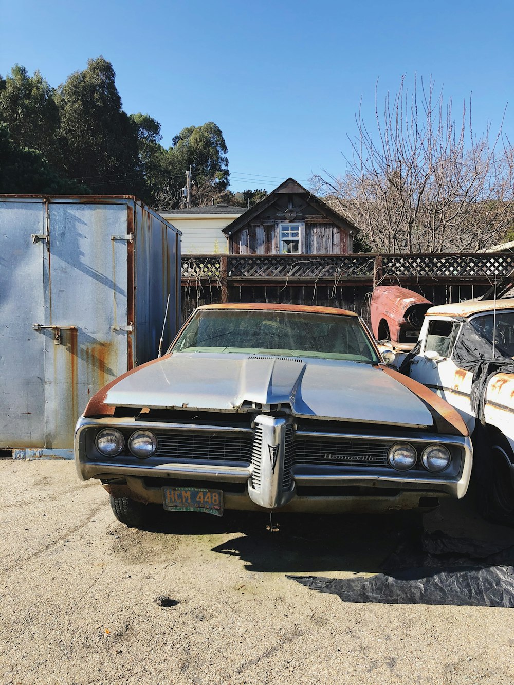 blue classic car parked beside brown wooden house during daytime