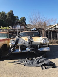 two old cars parked in a driveway next to each other