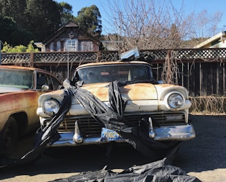 two old cars parked in a driveway next to each other