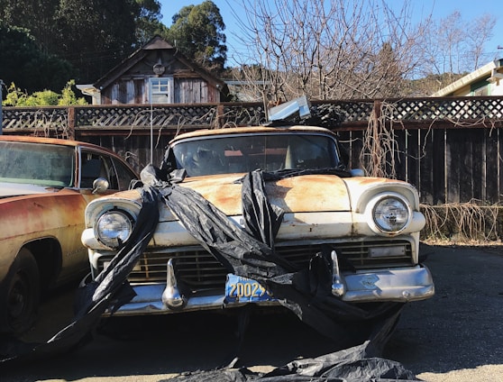 two old cars parked in a driveway next to each other