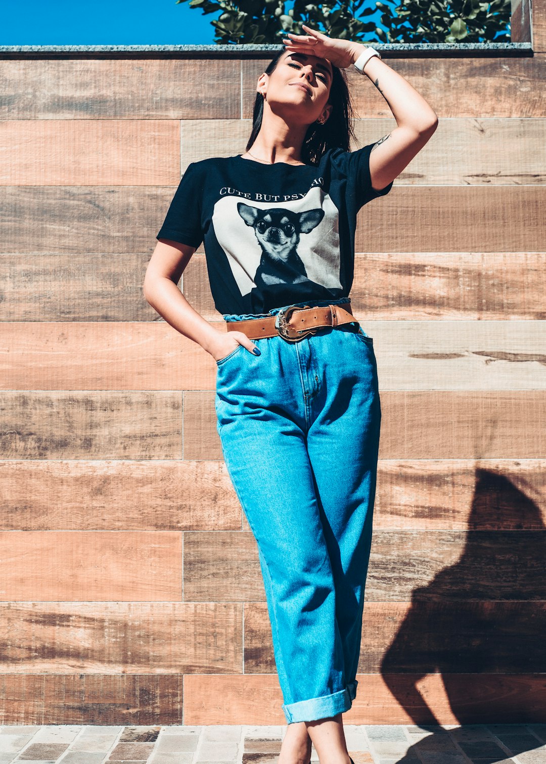 woman in black and white t-shirt and blue denim jeans standing on brown wooden floor