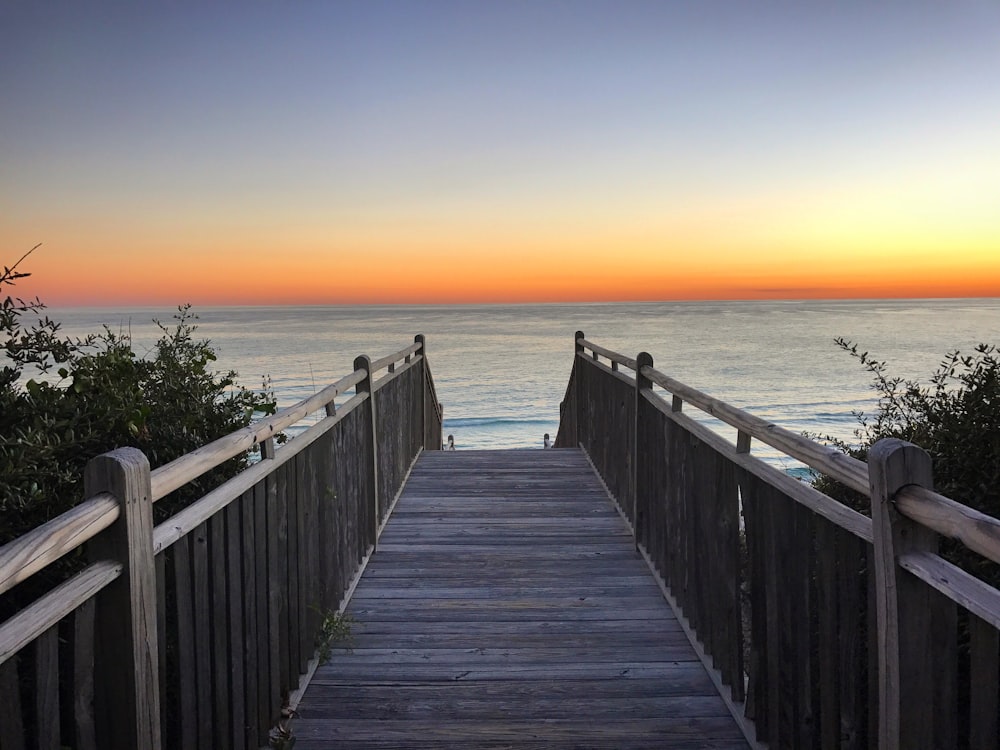 brown wooden dock on sea during sunset