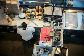 person in white shirt and black pants standing in front of kitchen sink