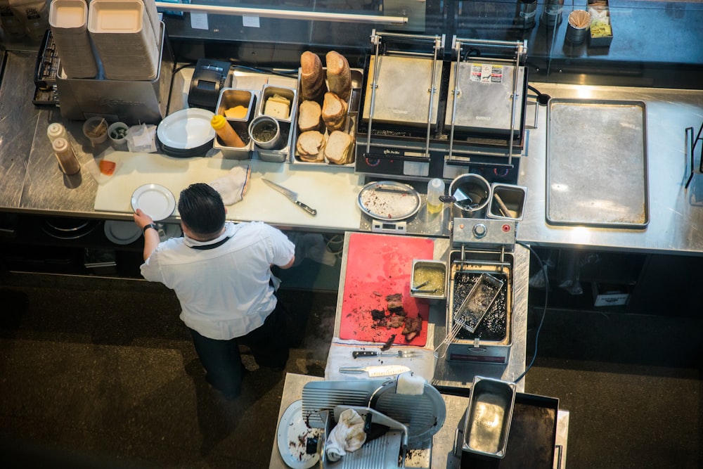 person in white shirt and black pants standing in front of kitchen sink