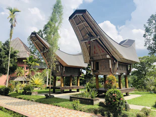 brown wooden house surrounded by green trees under blue sky during daytime