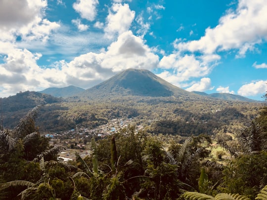 green and brown mountain under blue sky and white clouds during daytime in Minahasa Indonesia