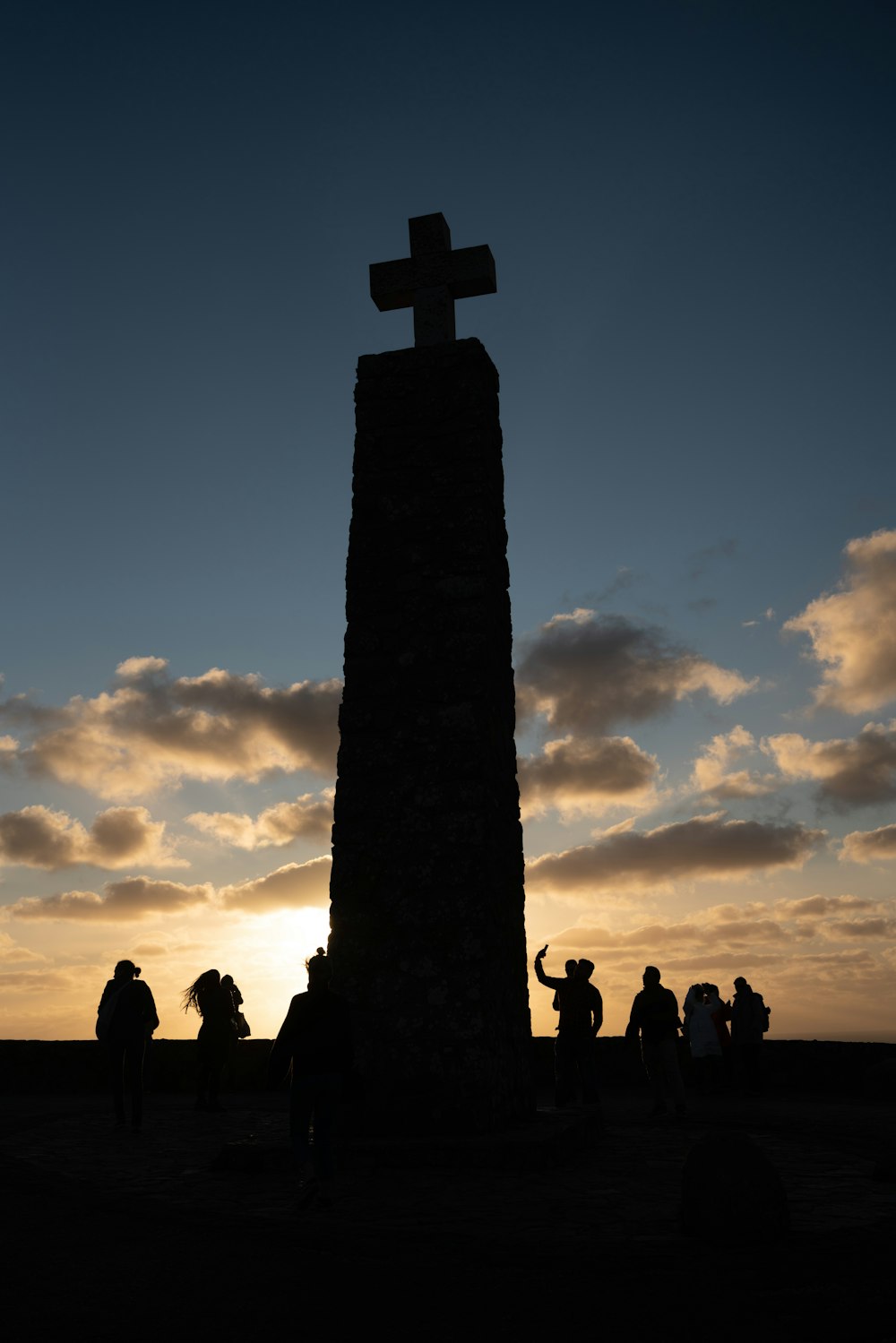 silhouette of people standing near cross under cloudy sky during daytime