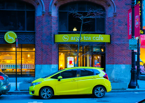 A compact car parked in front of a cozy café on a sunny day