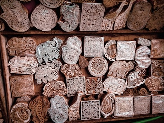 Intricately carved wooden blocks with various patterns and designs, including animals and geometric shapes, are arranged in a wooden drawer.