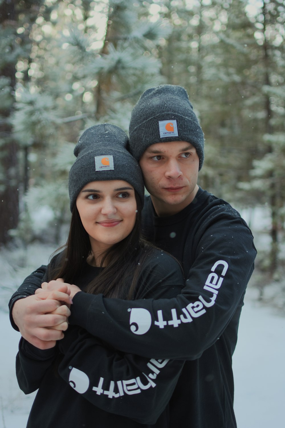 man and woman wearing black jacket and knit caps smiling