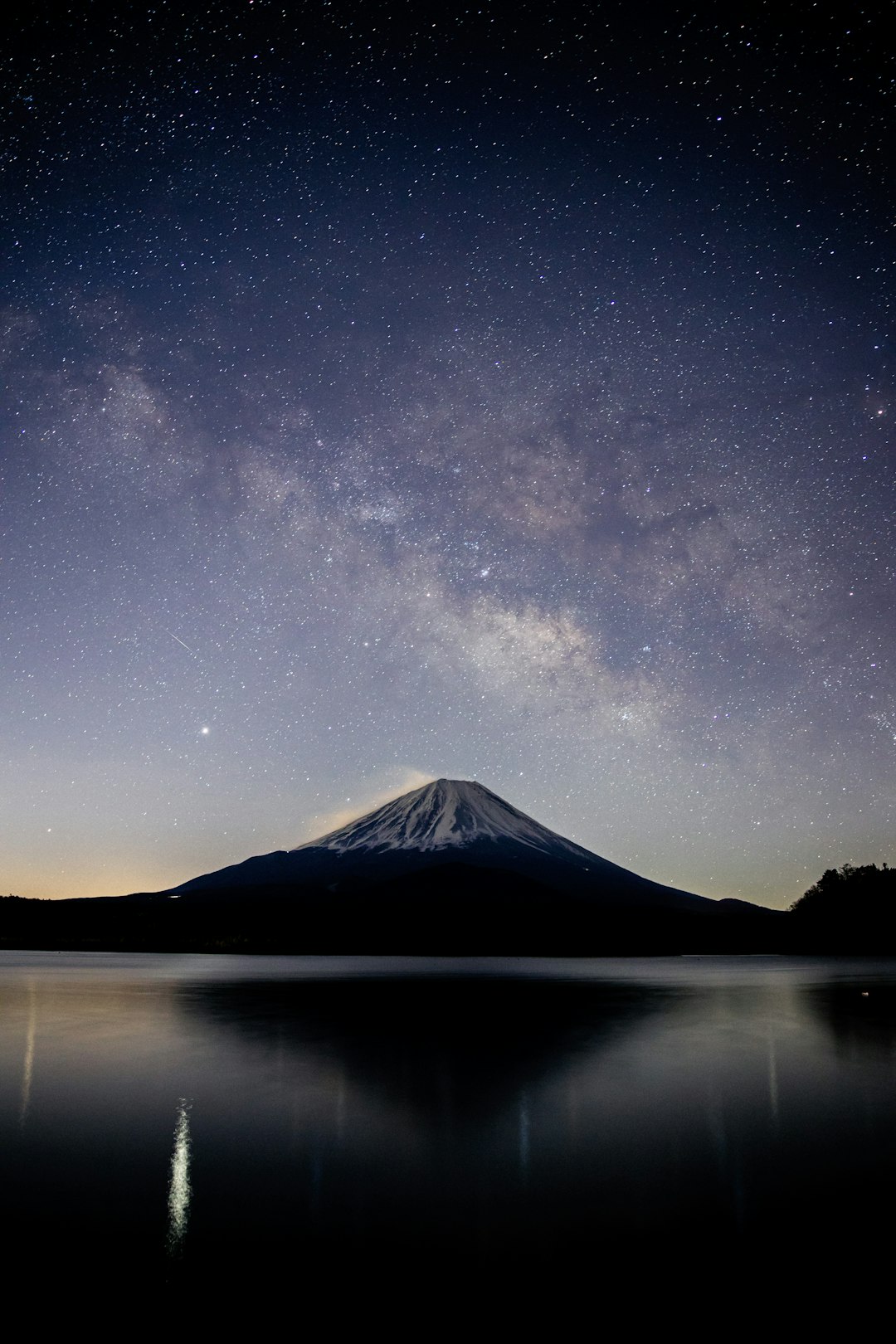 snow covered mountain near lake under starry night