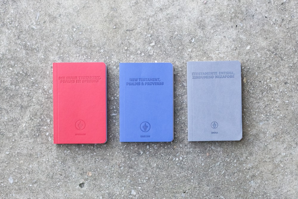 three red blue and green books on gray concrete floor