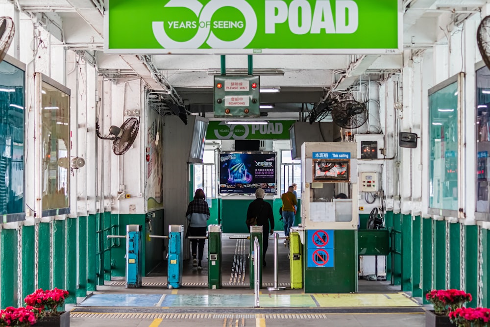 woman in green shirt and black pants standing near green and white food stall