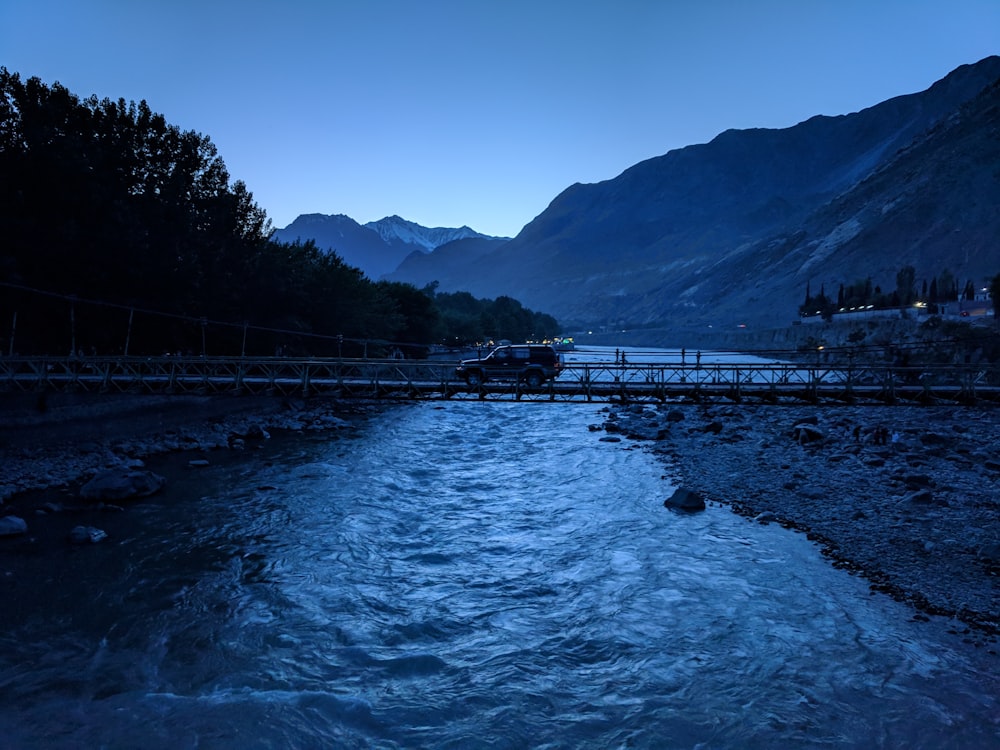 bridge over river near mountain during daytime